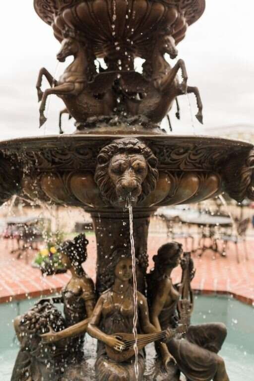 Bronze fountain with water cascading down. Sculptures include horses, lions, and nude women.
