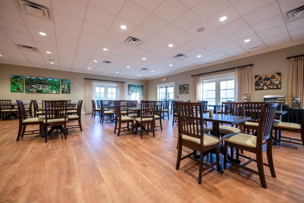 Dining room with round tables, wooden chairs, and artwork on the walls.