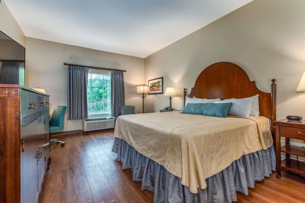 Bedroom with a queen bed, wooden furniture, and a window with blue curtains.