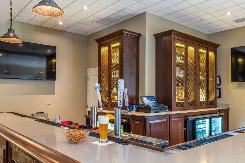Bar interior with wood cabinets, beer taps, drinks, and TVs.