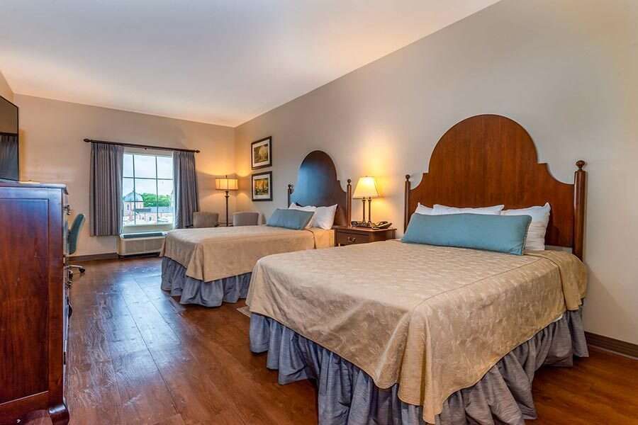 Two queen beds in a hotel room with brown and blue accents.